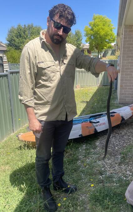Orange snake catcher Jake Hansen with a snake caught in a residential area. Picture supplied