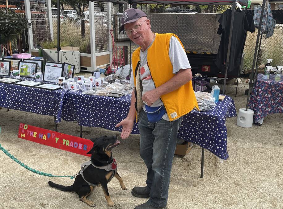 Volunteer organiser of the Trash and Treasure Markets Ken Shaw, out the front of his dog food stall, The Happy Trader, feeding Joey the Rescue Dog. Picture by Alise McIntosh