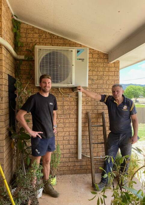 Dave Conyers (right) with his son Lachlan installing air conditioning units on one of his first trips to Eugowra. Picture supplied