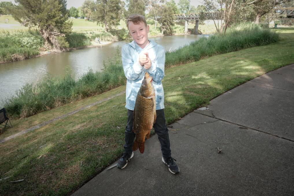 Ralph Lawson, 10, holding up the massive carp he caught in the Macquarie River. Picture by James Arrow