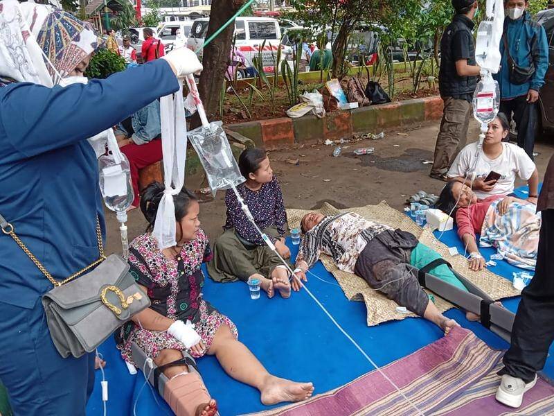 Injured people are being treated in a hospital car park after a deadly earthquake shook Indonesia. (AP PHOTO)